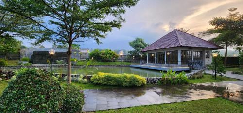 un petit bâtiment avec un étang dans un parc dans l'établissement PEPABRI Hotel & Resort, à Tjilimus
