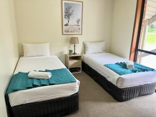 1 dormitorio con 2 camas y mesa con lámpara en Warragul Views Motor Inn, en Warragul