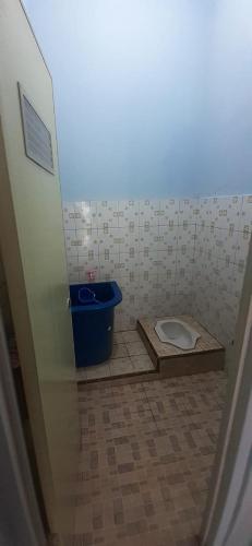 a bathroom with a toilet and a blue bucket at VILLA INTAN PALEMBANG in Talangbetutu