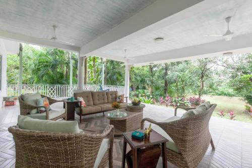 an outdoor living room with wicker chairs and tables at Vanya Farms by StayVista - Orchard villa with rustic vintage interiors & a table tennis table in Alībāg