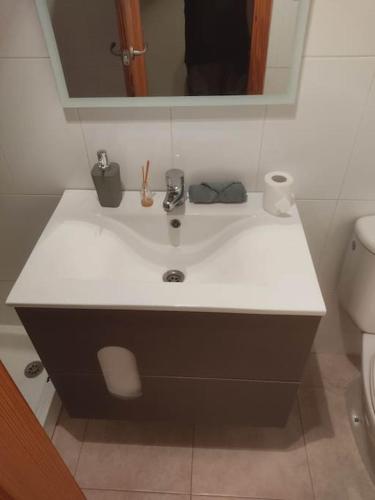 La salle de bains est pourvue d'un lavabo blanc et d'un miroir. dans l'établissement Tranquilo apartamento de pueblo, à Benifairó de Les Valls