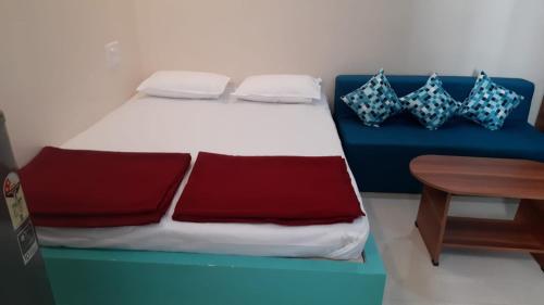 Una cama con sábanas rojas y azules y una mesa de madera. en Jenukal Nilaya en Mysore
