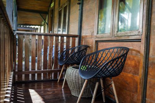 3 sedie sedute sul portico di una cabina di Sumatra Surf Resort a Biha