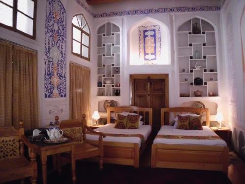 a room with two beds and two tables and a window at Emir in Bukhara