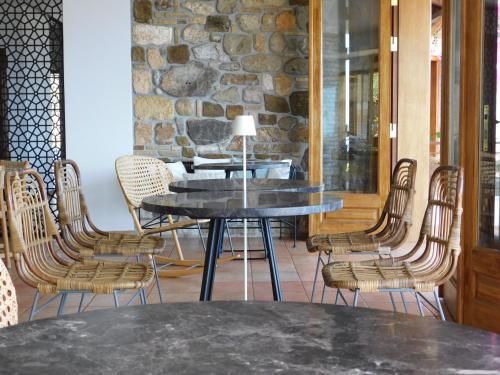 uma mesa e cadeiras num quarto com uma parede de pedra em Yialasi Hotel em Ancient Epidavros