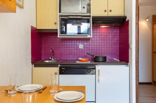 une cuisine avec du carrelage rose sur le mur dans l'établissement Résidence La Verte 12 ski in ski out - Happy Rentals, à Chamonix-Mont-Blanc
