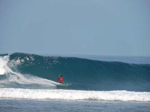 a man riding a wave on a surfboard in the ocean at Sumatra Surf Resort in Biha