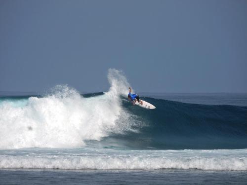 a man riding a wave on a surfboard in the ocean at Sumatra Surf Resort in Biha
