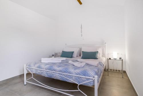 a white bed with blue and white sheets and pillows at Scorpios View Meganisi in Meganisi