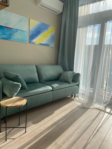 a living room with a green couch in front of a window at LeHome Airport Wroclaw in Wrocław