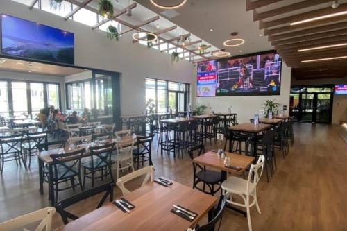 a restaurant with tables and chairs and a large screen at Zenhouse: 4BR Stylish Work/Family Home in Muirhead in Leanyer