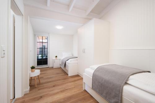 a white bedroom with two beds and a window at Hotel Haus am Park in Borkum