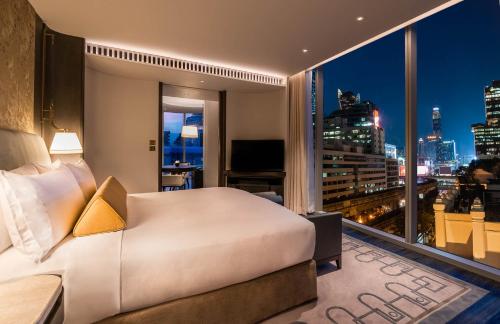 a bedroom with a bed and a view of a city at Waldorf Astoria Bangkok in Bangkok
