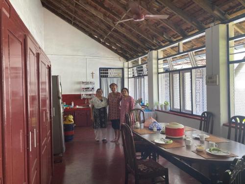 three people standing in a kitchen with a table at Walton's Homestay, Fort Cochin in Fort Kochi