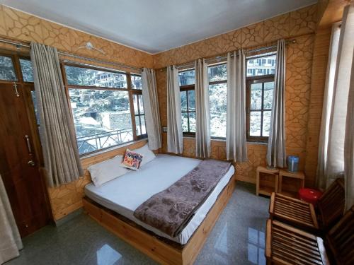 The MoonLight Stay - Shimla في شيملا: غرفة نوم مع سرير في غرفة مع نوافذ