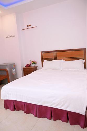 a bedroom with a large white bed with a wooden headboard at Khách sạn Hoàng Hà River Town in Yên Bái