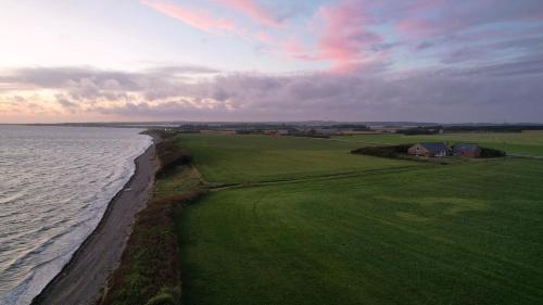 an aerial view of a green field next to the ocean at Villa Vandkant in Thyholm