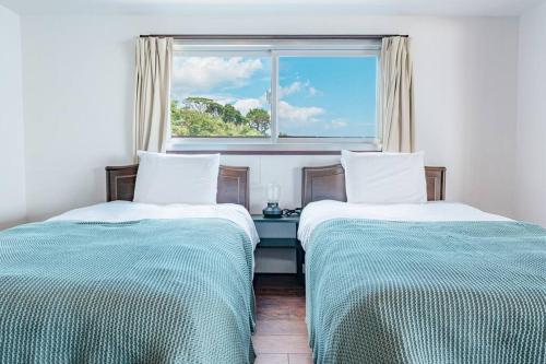 Harada的住宿－白浜大洋マンション，带窗户的客房内的两张床