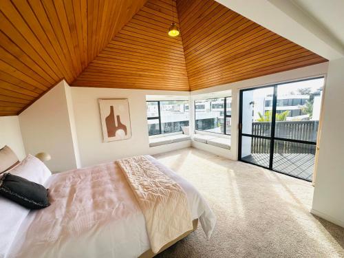 a bedroom with a large bed with a wooden ceiling at Spacious Mission Bay Villa 100m to the beach, seaview, private garden, Netflix in Auckland