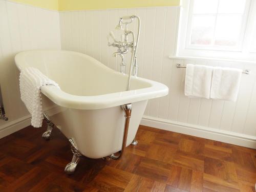 eine weiße Badewanne in einem Badezimmer mit Fenster in der Unterkunft Pump Cottage in Weymouth