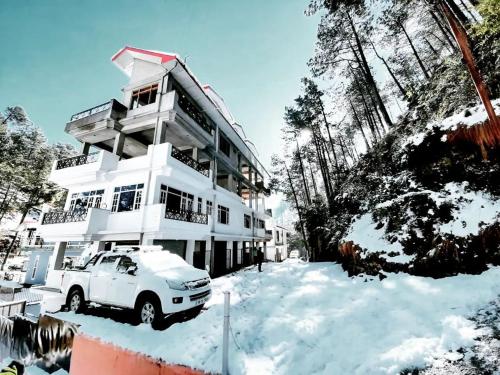 a white truck parked in front of a house in the snow at The MoonLight Stay - Shimla in Shimla
