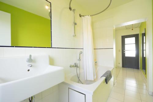 La salle de bains est pourvue d'un lavabo, d'une baignoire et d'un miroir. dans l'établissement Togo Guesthouse, à Tervuren