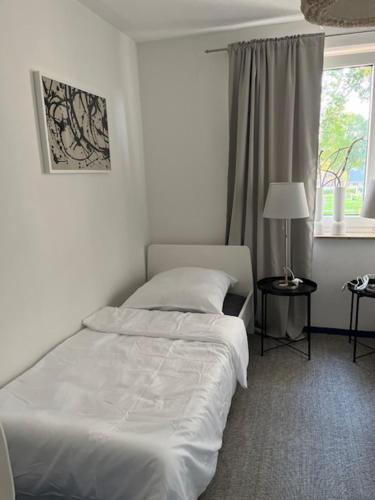 a white bedroom with a bed and a window at Green Space in Scheeßel