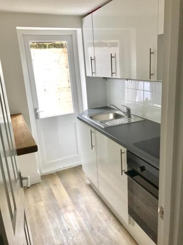 a white kitchen with a sink and a window at London Home in London