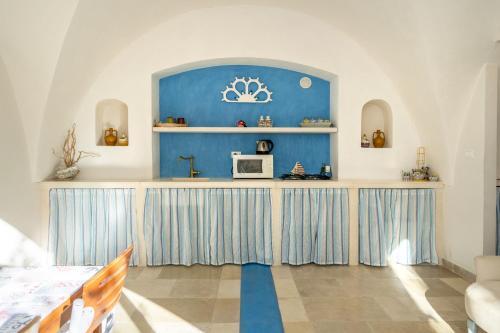 a room with a blue wall and a counter with a microwave at Agrumeto sul mare in Ostuni