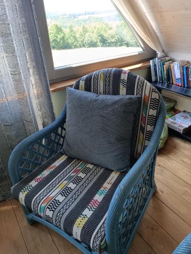 a blue wicker chair with a pillow and a window at Chatka na Wzgórzu in Morzyszów