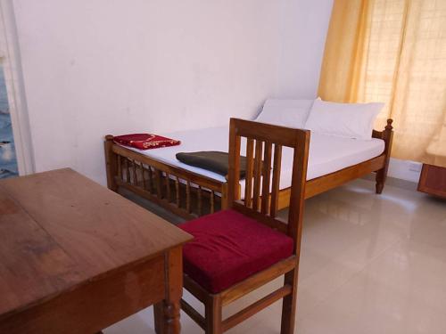 Somatheertham Ayurvedic Resort في تريفاندروم: غرفة نوم بسرير مع كرسي وطاولة