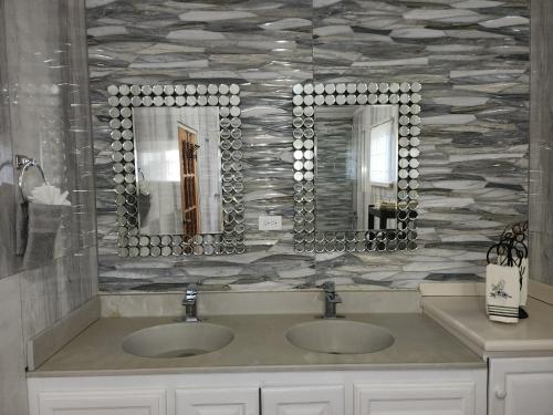 a bathroom with two sinks and two mirrors at 11onEssex1 in the heart of Kingston Ja DN Vacations in Kingston