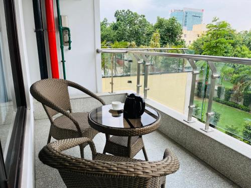 a table and two chairs on a balcony with a window at Gazebo Inn & Suites Medanta in Gurgaon