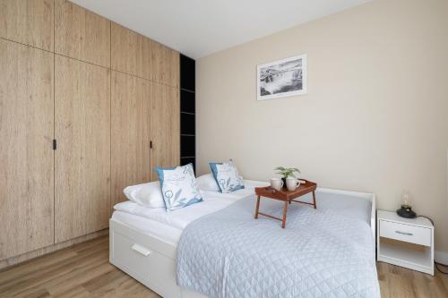 een slaapkamer met een wit bed en een houten kast bij Tauron Arena Crakow Apartment with Parking by Renters in Krakau