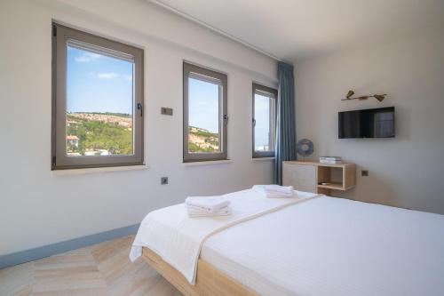 a white room with a bed and two windows at La Luz Bozcaada in Bozcaada