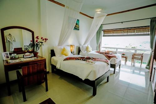 a bedroom with two beds and a desk and a mirror at Luangprabang View Hotel in Luang Prabang