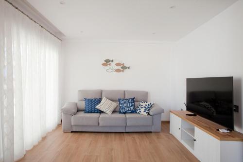 een woonkamer met een bank en een flatscreen-tv bij Acogedor apartamento junto al mar in Oliva