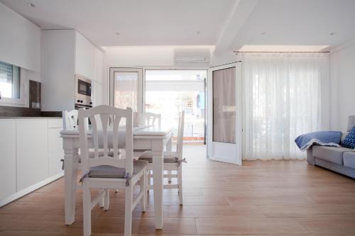 奧利瓦的住宿－Acogedor apartamento junto al mar，厨房以及带白色桌椅的用餐室。