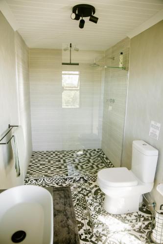 a bathroom with a white toilet and a shower at Breathe Accommodation in Oudtshoorn