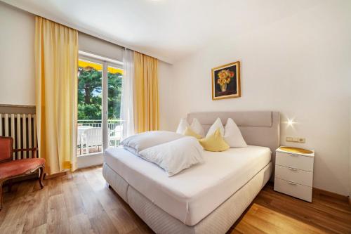 Un dormitorio con una cama blanca y una ventana. en Villa Sabine - Sabine, en Merano