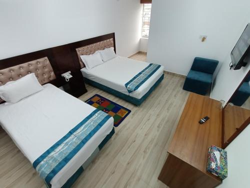 Pokój hotelowy z 2 łóżkami i krzesłem w obiekcie Hotel D-Palace w mieście Dhaka