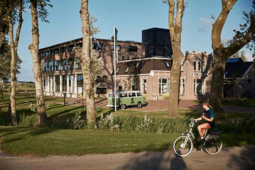 Una donna in bicicletta davanti a un palazzo di Suvelfabryk a Lioessens
