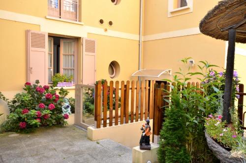 a fence in front of a house with flowers at Hôtel du Fort in Meulan