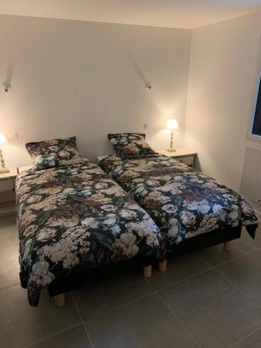 um quarto com duas camas com flores em La Vallée d'émeraude em Plouër-sur-Rance
