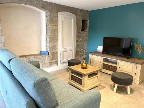 uma sala de estar com um sofá azul e uma televisão em La Vallée d'émeraude em Plouër-sur-Rance
