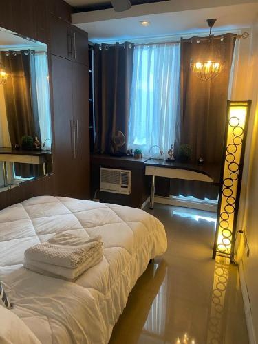 a bedroom with a large white bed and a window at Elegant 2BR, 2 BA Suite Beside Eastwood Mall in Manila