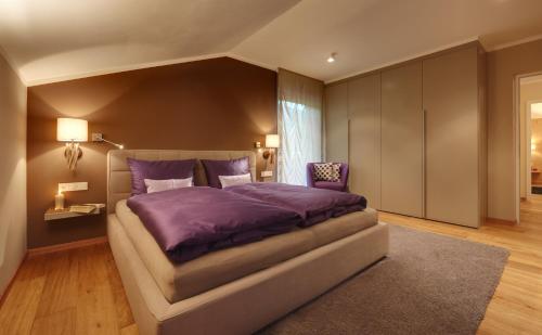 ein Schlafzimmer mit einem großen Bett mit einer lila Bettdecke in der Unterkunft Crioli Dolomiti Lodge in Niederdorf