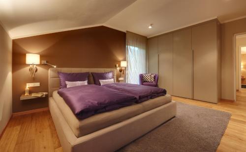 a bedroom with a large bed with a purple comforter at Crioli Dolomiti Lodge in Villabassa