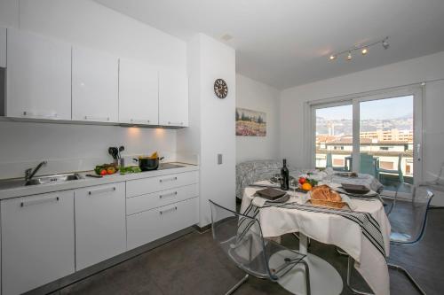 ルガノにあるSunrise House - Happy Rentalsの白いキャビネットとテーブル(食べ物付)が備わるキッチン