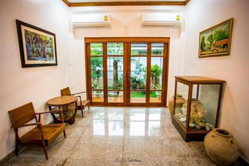 a living room with a table and chairs and a window at Tree Home Plus in Nakhon Si Thammarat